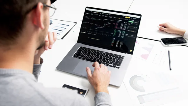 Business professional analyzing stock market data on a laptop for investment insights. Økonomiske nøgletal: Sådan bruger du dem